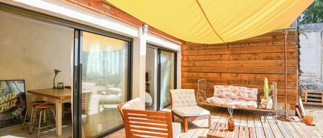 A wooden deck with a table, chairs, and a sofa.