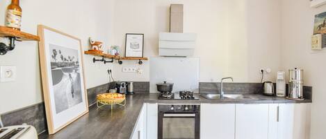 A compact kitchen with a built-in oven, a coffee maker, and a sink.
