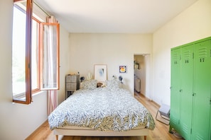 A bedroom with a bed, a window, a green wardrobe, and a door leading to another room. - Maison avec terrasse & parking - Chartreux (Marseille)
