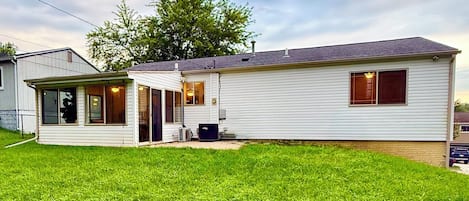 A single-story mobile home with a covered porch, a small attached garage, and a well-maintained lawn.