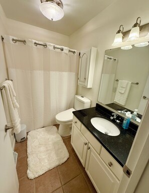 A bathroom with a white toilet, a sink with a mirror above it, and a shower curtain. - EV charger modern 4 bedroom, 3 Bathroom house in great neighborhood Cedar Rapids (Cedar Rapids)