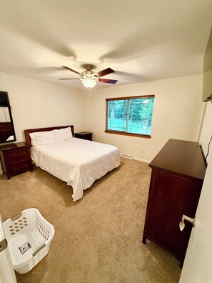 A bedroom with a bed, a ceiling fan, a window with blinds, a dresser, and a nightstand. - EV charger modern 4 bedroom, 3 Bathroom house in great neighborhood Cedar Rapids (Cedar Rapids)