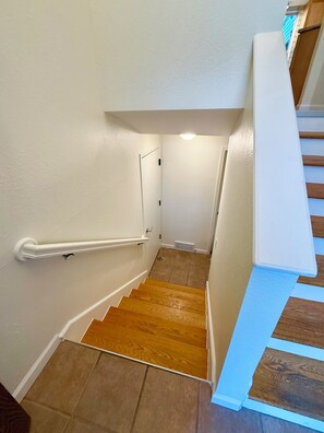 A staircase with wooden steps and white walls, leading to a landing with a white handrail.