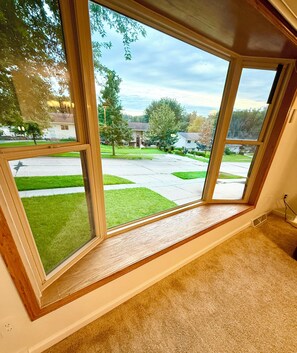 A room with a large window overlooking a suburban street with houses and greenery. - EV charger modern 4 bedroom, 3 Bathroom house in great neighborhood Cedar Rapids (Cedar Rapids)