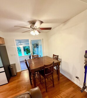 A dining area with a wooden table, four chairs, a ceiling fan, and a view of a garden through a glass door. - EV charger modern 4 bedroom, 3 Bathroom house in great neighborhood Cedar Rapids (Cedar Rapids)
