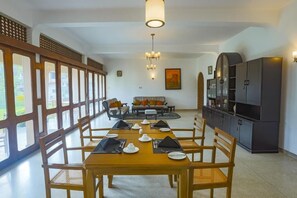 Un comedor con una larga mesa dispuesta para una comida, rodeada de sillas, y un sofá y un mueble de televisión al fondo.