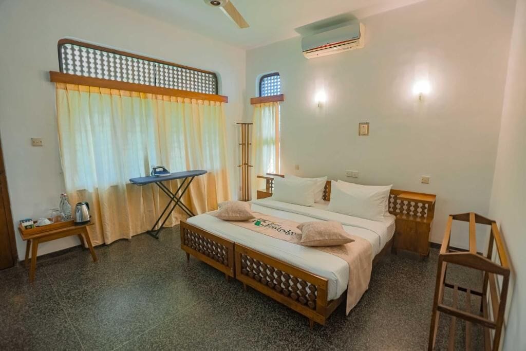 A bedroom with a bed, bedside tables, a desk, and curtains.