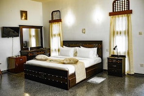 Un dormitorio con cama, cómoda, mesita de noche, espejo y televisión.