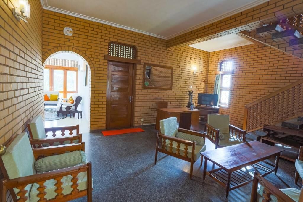 A room with brick walls, a wooden door, a television, and seating arrangements.