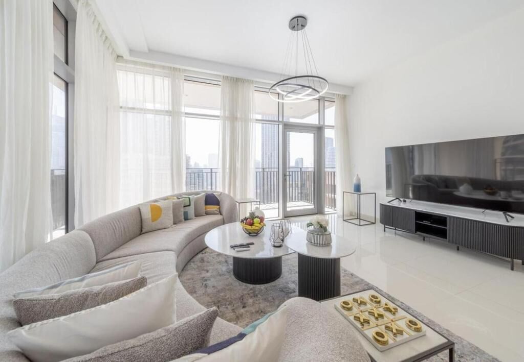 A modern living room with a curved sofa, a round coffee table, and a flat-screen TV.
