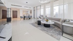 A modern living room with a sofa, coffee table, and dining area. - BLVD Crescent Tower 1 (Dubai)