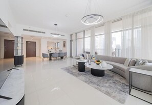 A modern living room with a sofa, coffee table, and dining area. - BLVD Crescent Tower 1 (Dubai)