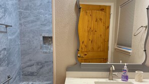 A bathroom with a shower, vanity, and a mirror.