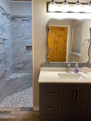 Un bagno con doccia, lavabo e specchio.