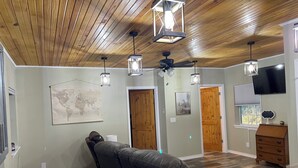 A room with a massage chair, wooden flooring, a world map, and a television.