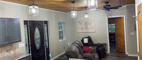 Un salon moderne avec un plafond en bois, un canapé, une table basse et une carte accrochée au mur.