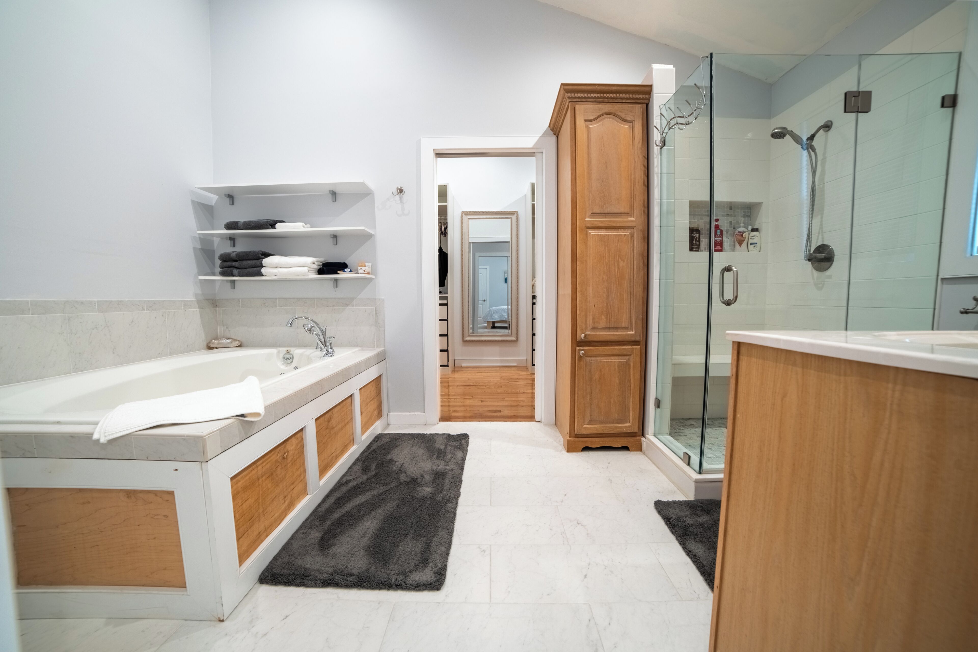 A modern bathroom with a bathtub, shower, and walk-in closet.