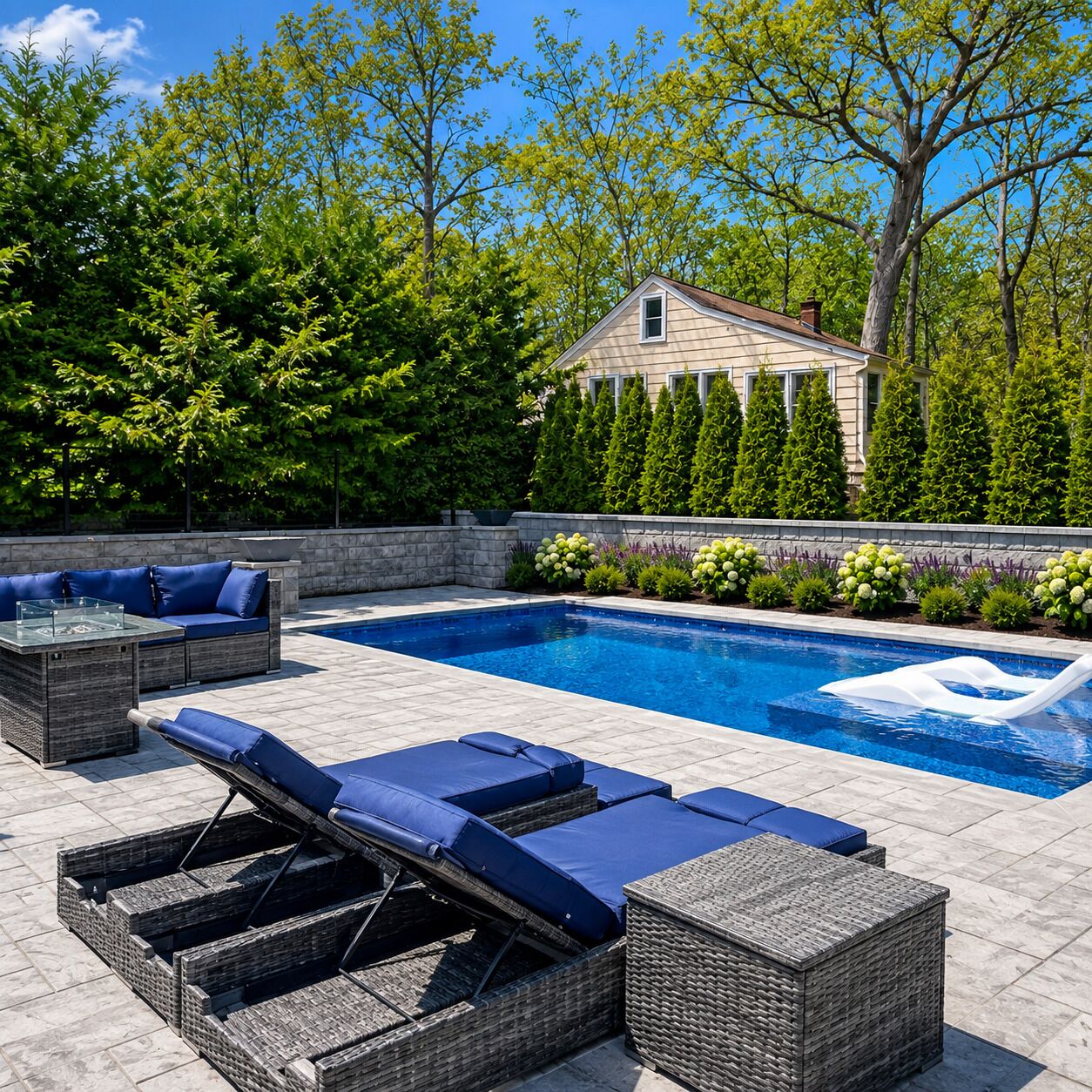 A swimming pool with lounge chairs and a stone wall.