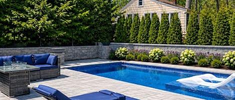 A swimming pool with lounge chairs and a stone wall.