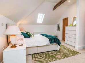 Ein Schlafzimmer mit Bett, Nachttischlampen, einem Schminktisch, einem Spiegel und einem Oberlicht.
