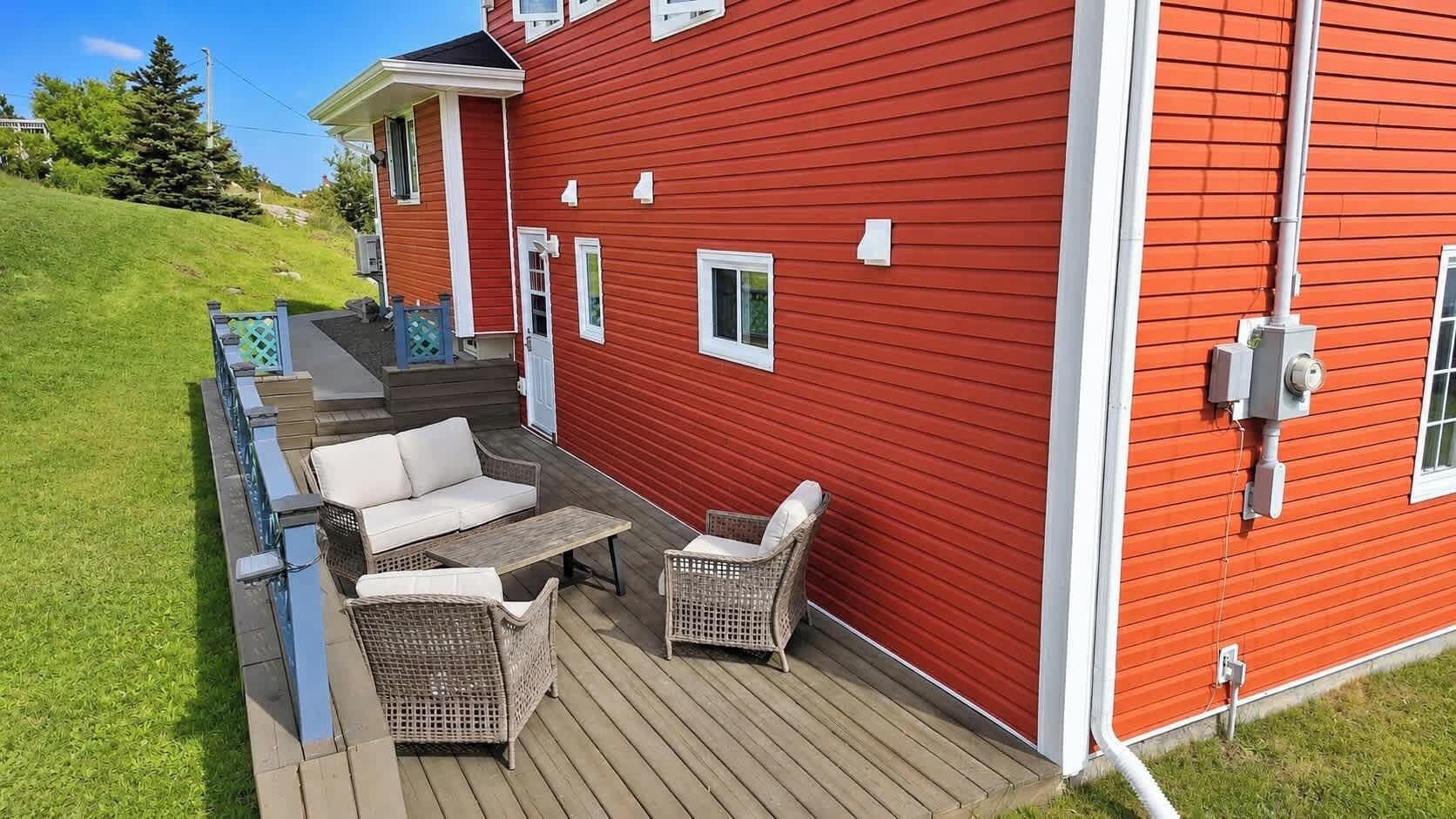 A red house with a wooden deck, outdoor furniture, and a mailbox.