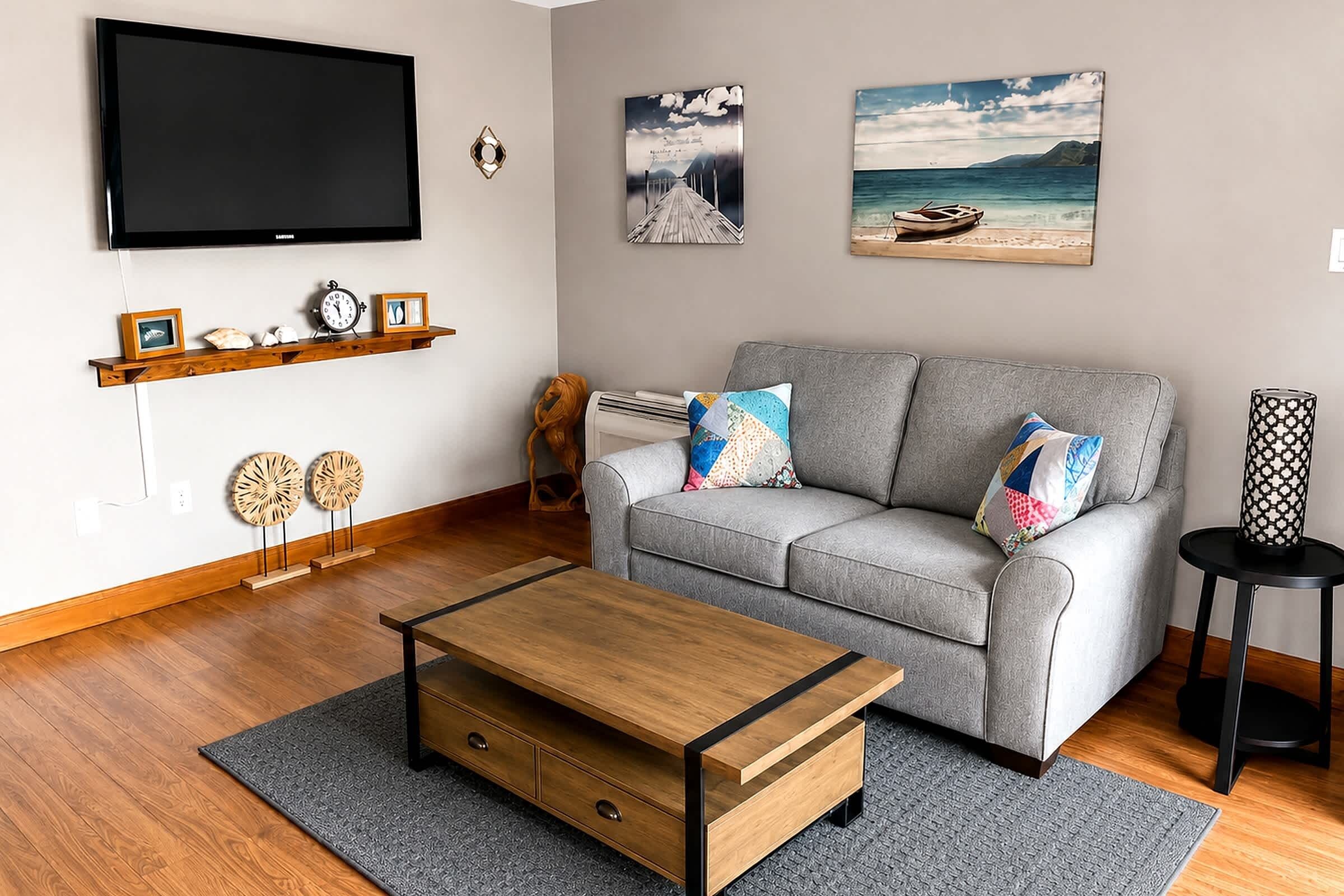 A living room with a grey sofa, wooden coffee table, and two wall-mounted paintings.