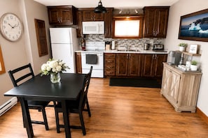 A kitchen with wooden cabinets, a white refrigerator, a microwave, and a dining table with chairs.