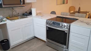 A modern kitchen with white cabinetry, a stainless steel stove, and a marble countertop. - Beautiful, brand-new, recently remodeled house with private parking (North Miami)