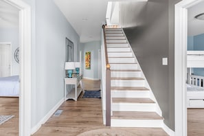 A staircase with wooden steps and a white handrail, leading to a bedroom with a bunk bed. - "Whispering Palms"5 bed/3.5bath w/pool/beach access (North Topsail Beach)