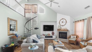 Una sala de estar amplia con chimenea, televisor y escalera.
