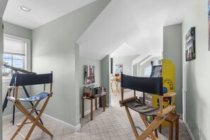 A room with two folding chairs, a window with blinds, and a wall with framed pictures. - "Whispering Palms"5 bed/3.5bath w/pool/beach access (North Topsail Beach)