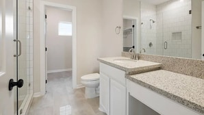 Une salle de bain avec une douche, des toilettes et un grand miroir.