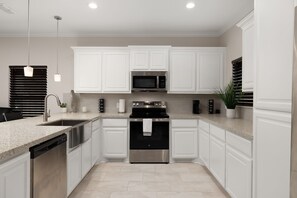 A modern kitchen with white cabinetry, stainless steel appliances, and a granite countertop. - Casa Jerez - Near Padre Island, Church & Hospital (San Juan)