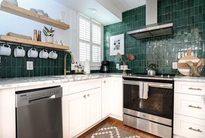 Een moderne keuken met witte kastjes, een vaatwasser, een oven en een koffiezetapparaat.
