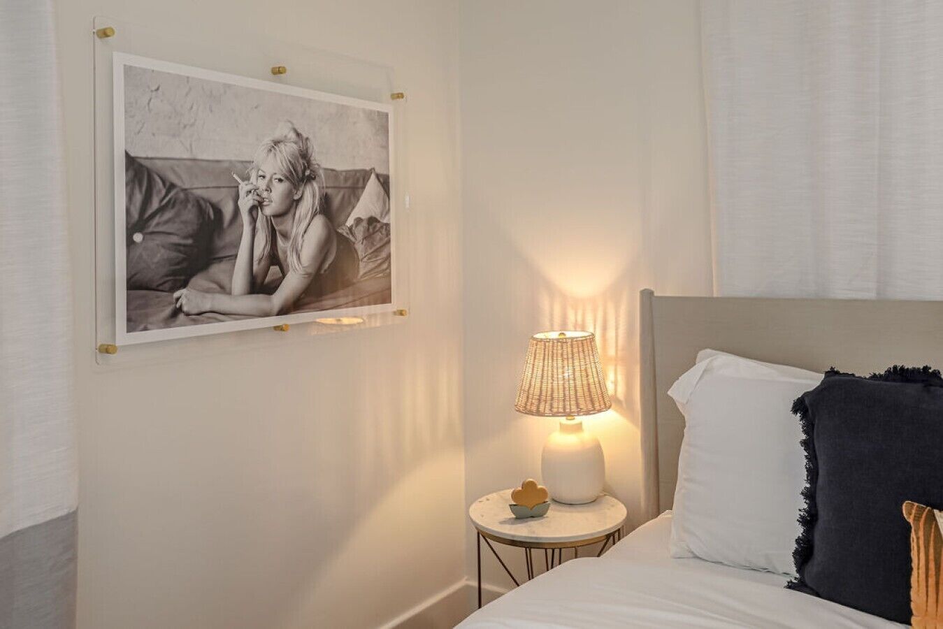 Un dormitorio con una cama, una mesita de noche con lámpara y un cuadro en la pared.