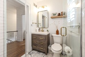 Een badkamer met een houten wastafelmeubel, een wit toilet en een douchecabine met glazen wanden.