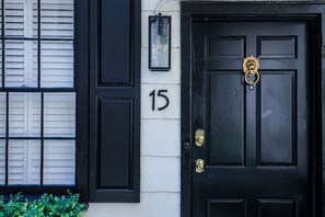 A black door with a brass knocker and a number '15' on the wall.