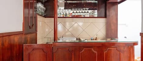 A bar area with a wooden counter and a tiled backsplash.
