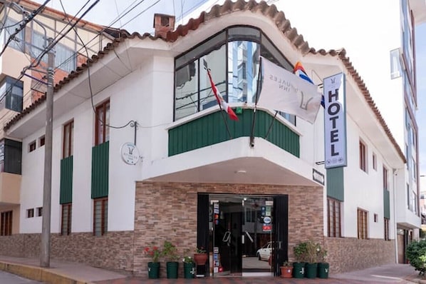 A hotel with a curved facade, a prominent entrance, and a sign indicating it is a hotel. - Rituales Inn Romeritos (Cusco)