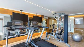 Un gimnasio con cintas de correr, máquinas de pesas y pelotas de ejercicio.