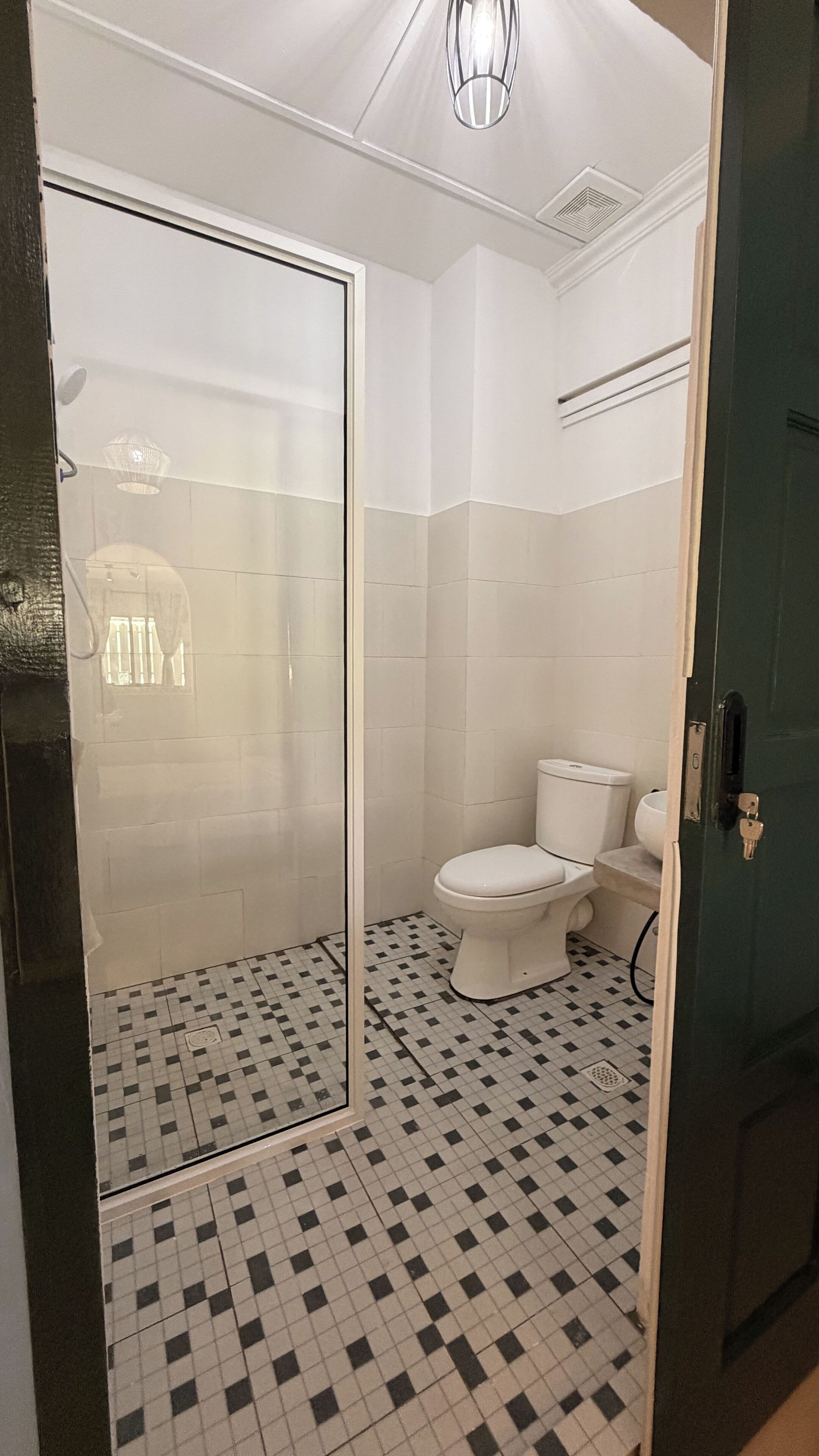 A bathroom with a shower enclosure, toilet, and tiled floor.