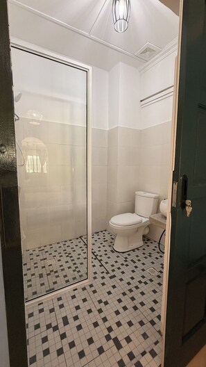 A bathroom with a shower enclosure, toilet, and tiled floor. - Embun at Sumbiling (Bandar Seri Begawan)