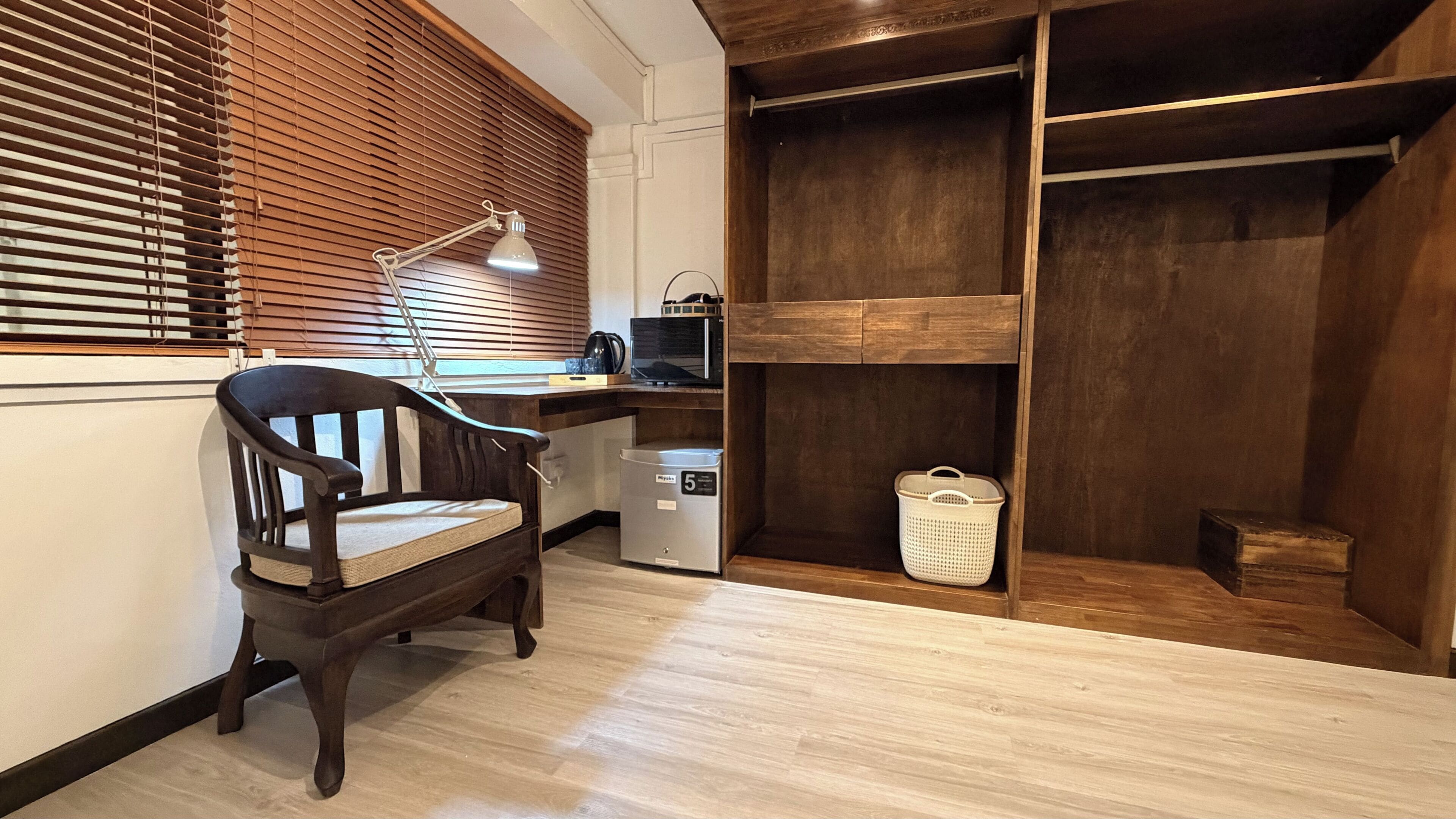 Une pièce comprenant un bureau en bois, une chaise, un four à micro-ondes, un lave-linge et une armoire en bois.