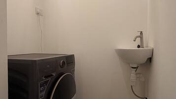 A compact laundry room with a washing machine and a sink.