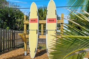 Dos tablas de rescate amarillas con la palabra 'RESCUE' escrita, sujetas a una estructura de madera, con una valla al fondo.