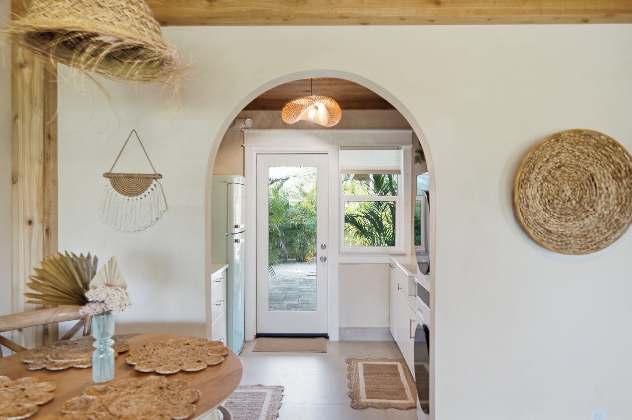 A kitchen with white cabinets, a wooden ceiling, and a view of the outdoors through a glass door.