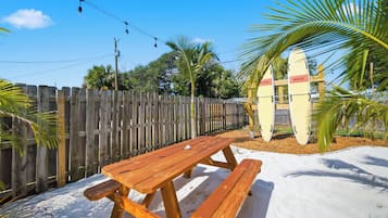 A wooden picnic table with benches, a wooden fence, and surfboards with 'RESCUE' written on them.