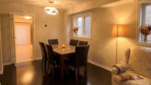 Uma sala de jantar com mesa e cadeiras, um abajur e uma janela com vista.