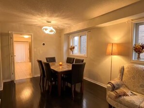 Spiseområde med et bord, stole, en lampe og et vindue med udsigt.