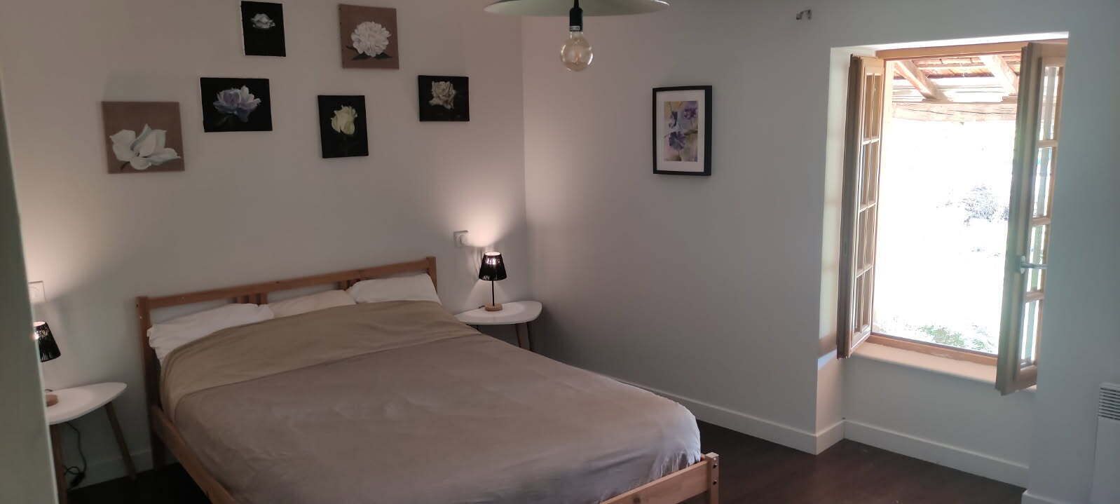 Une chambre à coucher avec un lit, des tables de chevet et des œuvres d’art accrochées au mur.